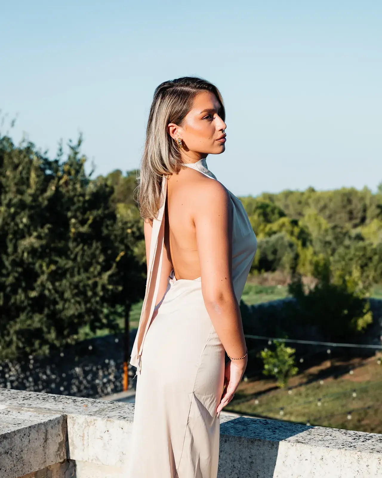 Una donna in abito lungo guarda il verde del Parco di Torcito nella luce del tramonto