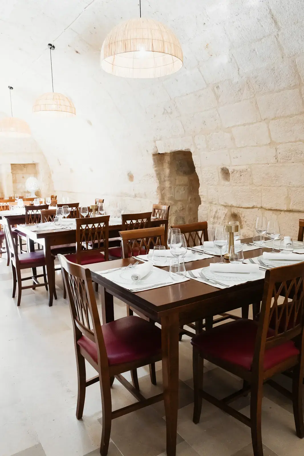 Calici di vino pugliese e mise en place nella sala in pietra del ristorante